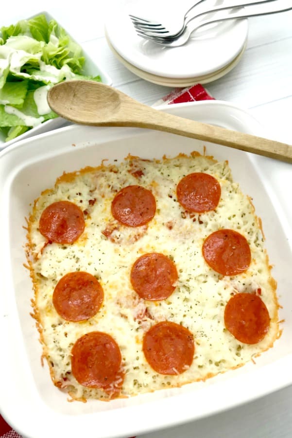 keto friendly pizza casserole in a white dish with a wooden spoon keto friendly pizza casserole in a white dish with a wooden spoon