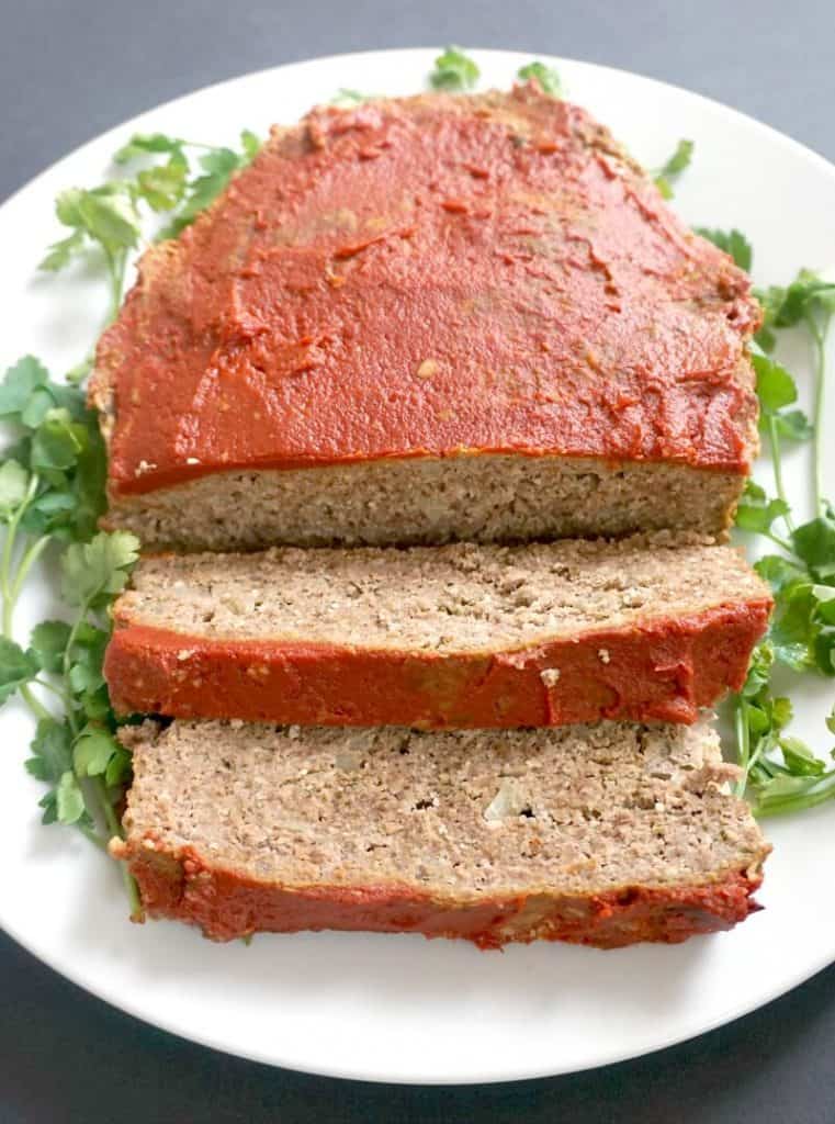 slower cooker keto meat loaf on a bed of greens on white plate slower cooker keto meat loaf on a bed of greens on white plate
