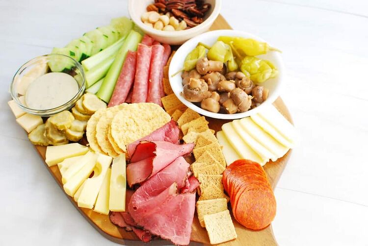 a low carb charcuterie board with keto crackers, pepperoni, salami, pastrami, cheeses, and vegetables