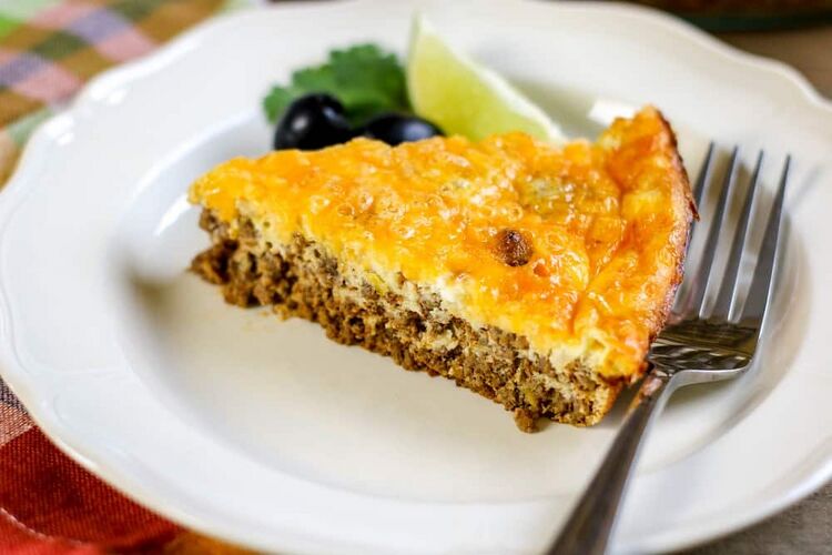 Keto taco pie on a white plate next to a fork