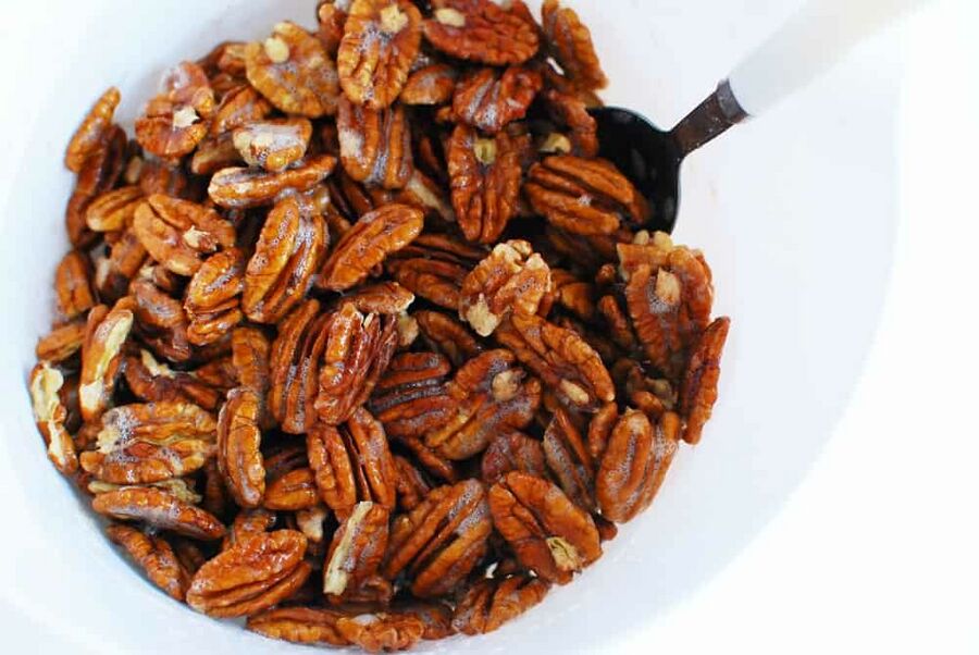Raw pecans tossed in an egg white mixture in a bowl Raw pecans tossed in an egg white mixture in a bowl