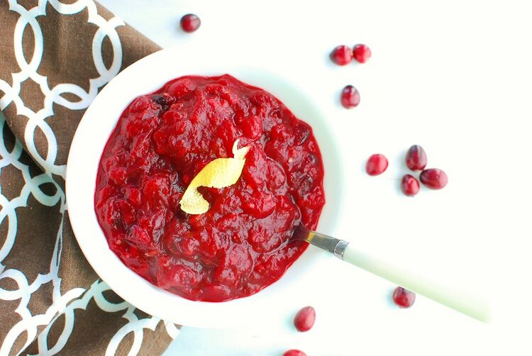 A white bowl full of keto cranberry sauce next to a brown napkin