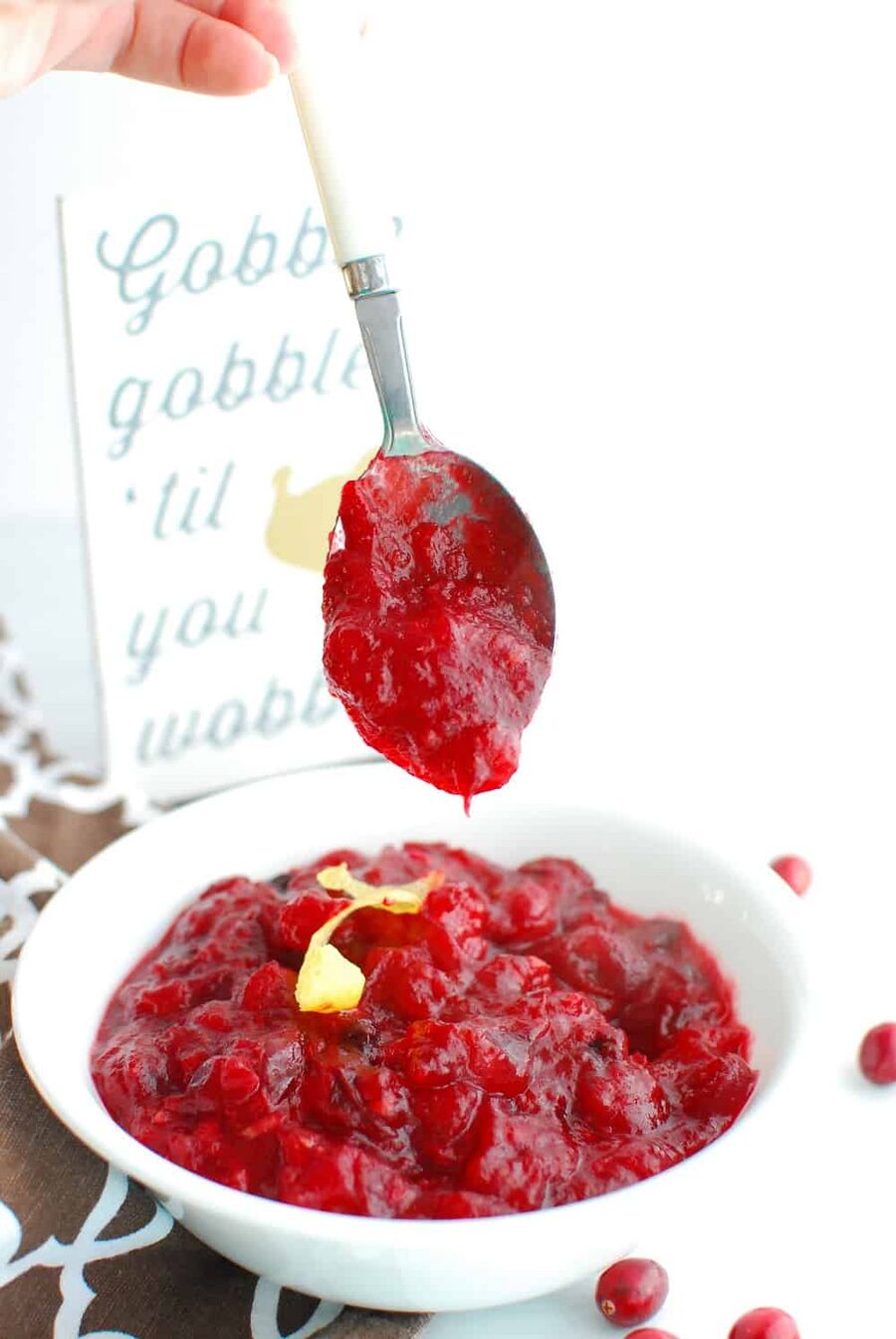 A spoon of low carb cranberry sauce dripping into a bowl full of it A spoon of low carb cranberry sauce dripping into a bowl full of it