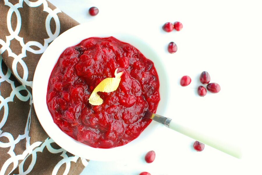 A white bowl full of keto cranberry sauce next to a brown napkin A white bowl full of keto cranberry sauce next to a brown napkin