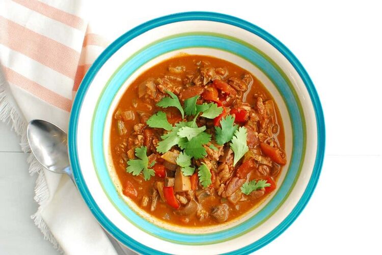 A bowl of keto vegan chili garnished with a few cilantro leaves.